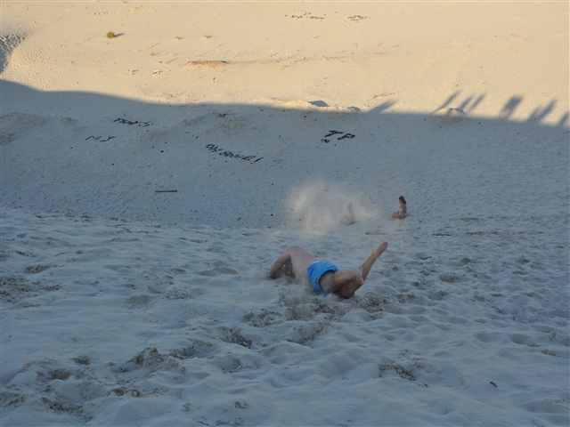 Francesco si lascia rotolare giù dal pendio della duna, verso valle, sollevando una nuvola di sabbia.